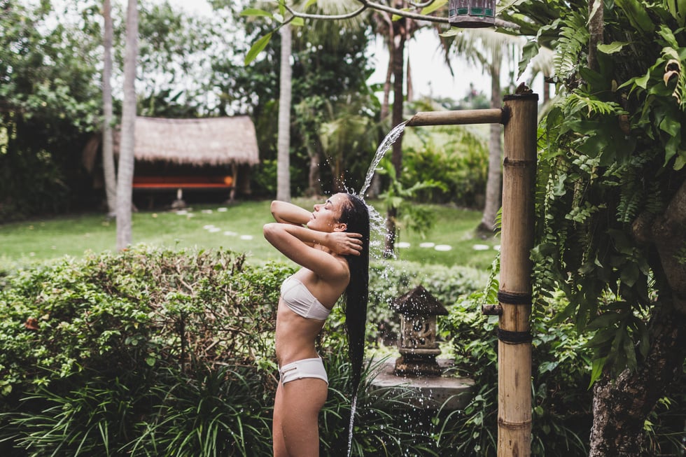 Slim brunette woman taking shower outdoor in tropical garden in Bali, organic skin care, luxury spa hotel, lifestyle photo